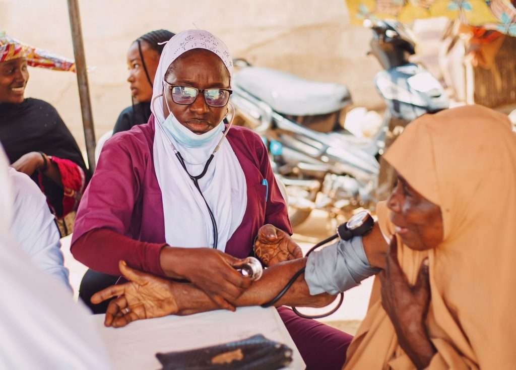 A community health worker attending to a patient outdoors